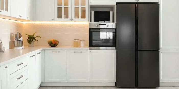 In einer weißen Küche steht ein schwarzer Kühlschrank