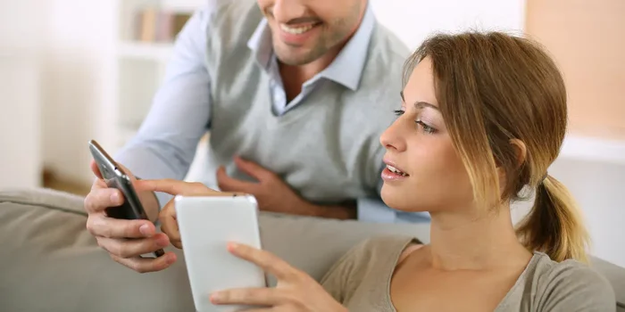 Mann und Frau nutzen Smartphones auf Sofa