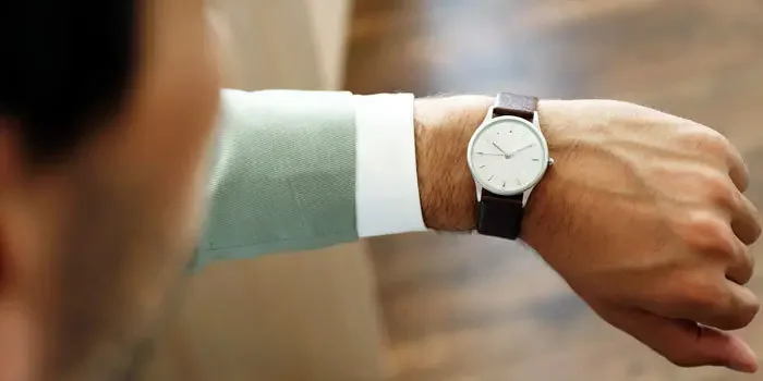 Aufnahme eines Mannes, welcher auf seine klassische Armbanduhr schaut.