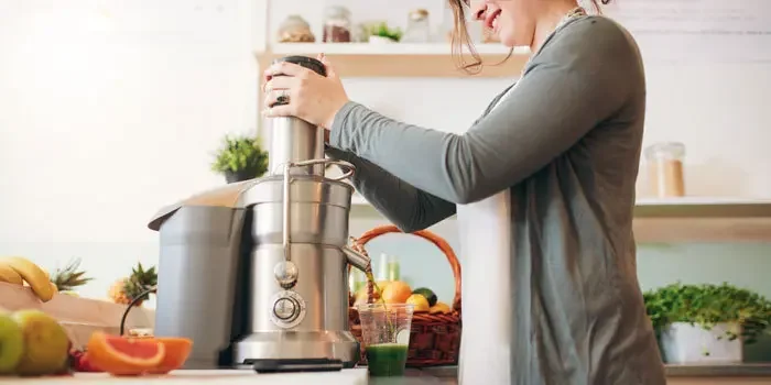 Frau erzeugt frischem Saft mit Hilfe einer Küchenmaschine