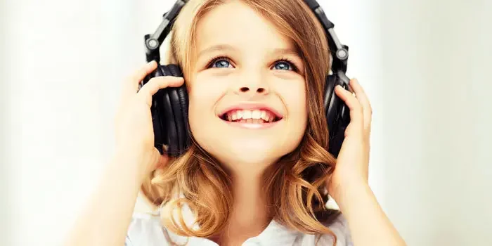 Junges Mädchen mit Funk-Kopfhörern hört lächelnd Musik