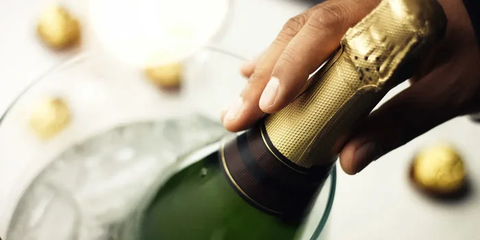 Eine Champagnerflasche mit sichtbarem Etikett liegt in einem Kühler