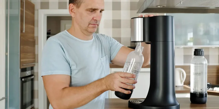 Mann steckt Karaffe in einen Wassersprudler