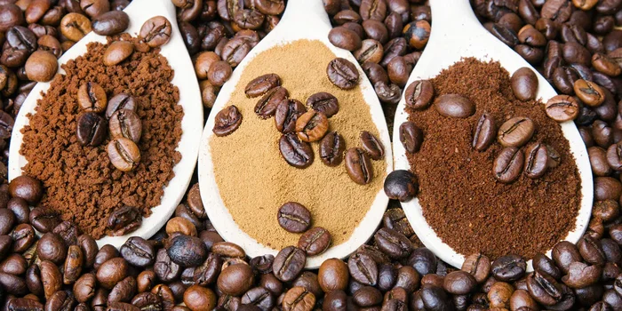 Löffel befüllt mit Kaffeegranulat, gemahlenem Kaffee und Kaffeepulver auf Kaffeebohnen