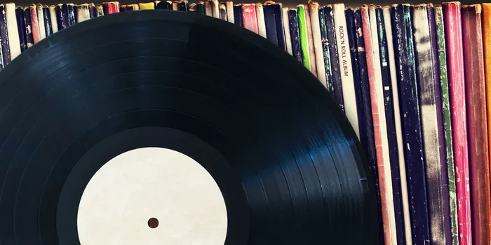 Vinylscheibe vor einer, in einem Regal aufgereihten, Schallplattensammlung