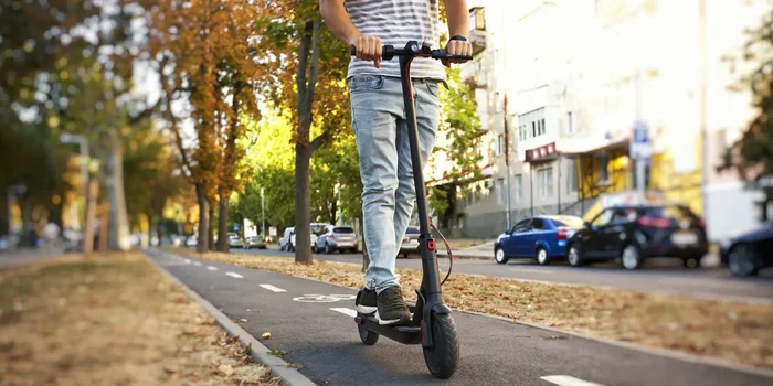 Mann fährt einen E-Scooter auf dem Radweg