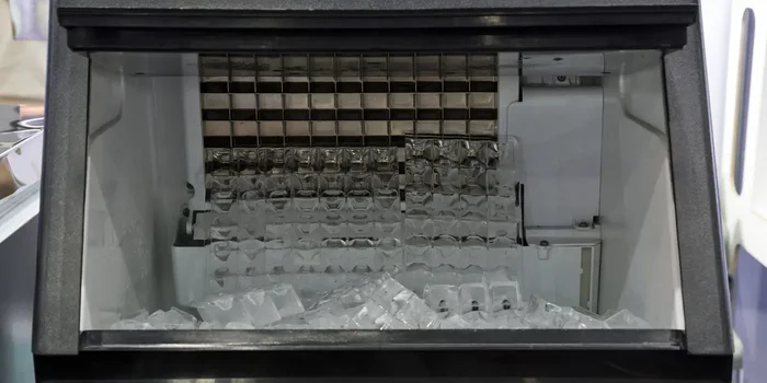 In der Auffangschale einer Eiswürfelmaschine liegen zahlreiche fertige Eiswürfel bereit