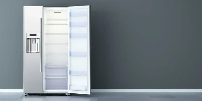 Edelstahlkühlschrank mit einseitig geöffneter Doppeltür vor grauer Wand