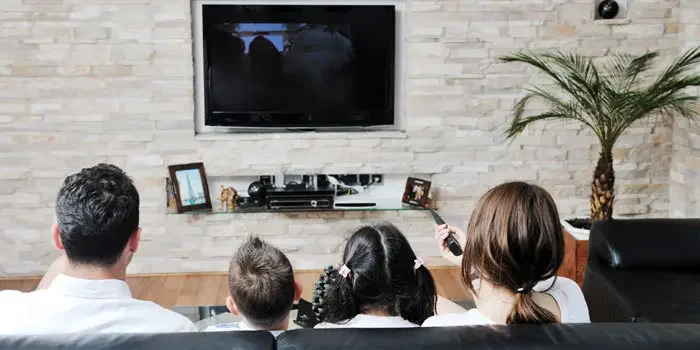 Junge Familie mit zwei Kindern sitzt gemeinsam vor dem Fernseher