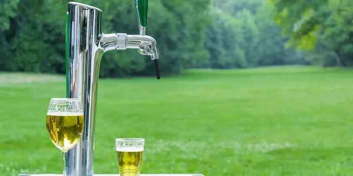 Mobile Bierzapfanlage mit zwei Gläsern Bier steht in einem Garten