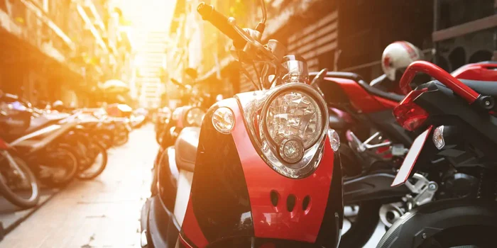 Frontansicht eines Motorrollers der auf einer Straße mit parkenden Motorrollern steht