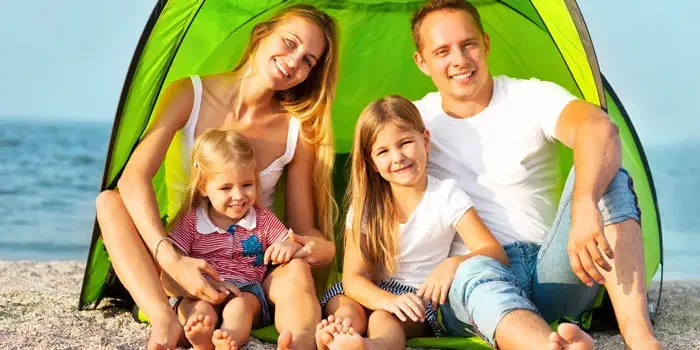 Junge Familie mit zwei Kindern in einer Strandmuschel am Strand sitzend