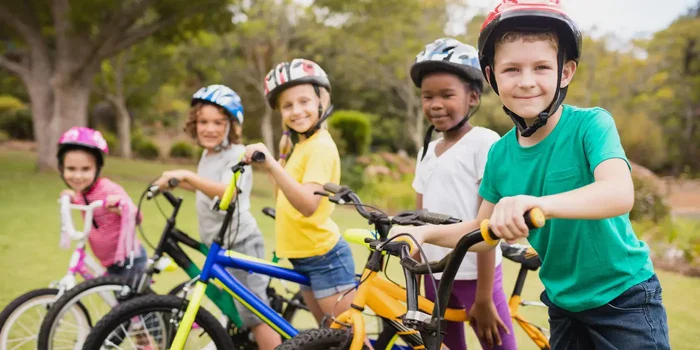 Fünf Kinder posieren mit ihren Fahrrädern im Park