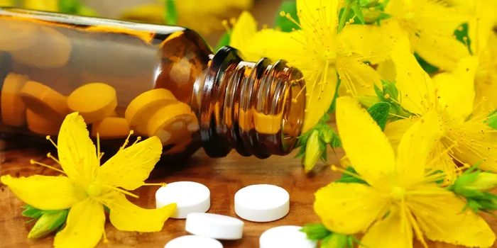 Nahaufnahme von gelben Blüten um ein liegendes Medikamentenfläschen mit weißen Tabletten