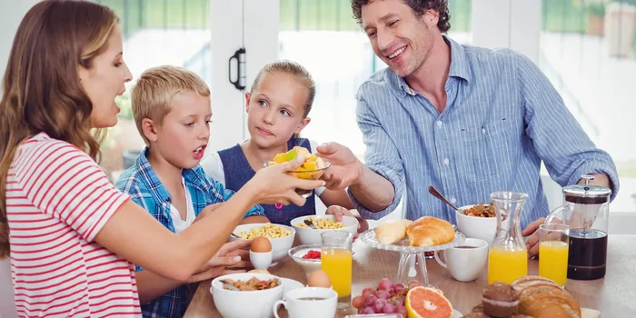 Ein Elternpaar frühstückt gemeinsam mit den zwei kleinen Kindern