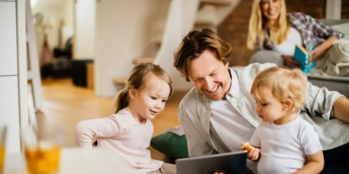 Ein Vater schaut mit seinen zwei kleinen Kindern ein Video auf dem Tablet