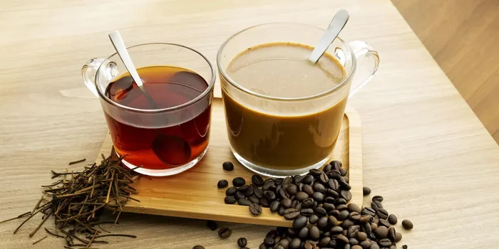 Ein Glas mit Tee und ein Glas mit Kaffee stehen auf einem kleinen Holztablett
