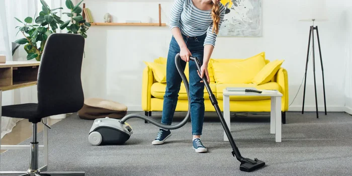 Frau saugt den Boden in ihrem Wohnzimmer