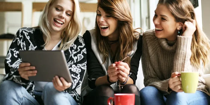 Gruppe junger Frauen sitzt beim Kaffee mit einem Tablet-PC zusammen