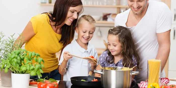 Eine Familie mit zwei Kindern bereitet Nudeln in der Küche zu