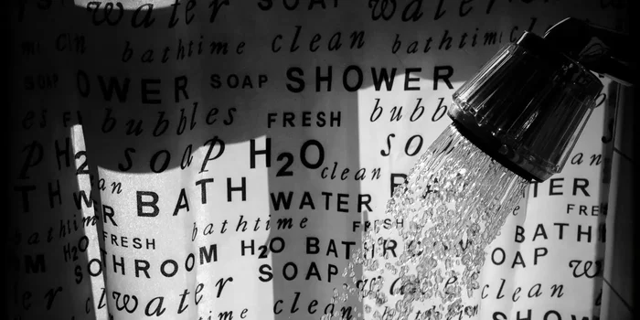 Schwarz-weiß Duschvorhang mit Stichwörter rund um das Duschen. Im Vordergrund fließt Wasser aus dem Duschkopf