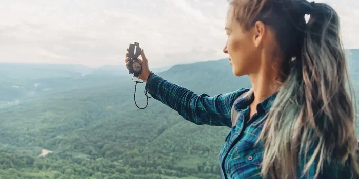 Eine Frau mit Kompass sucht die richtige Richtung auf einem Berg
