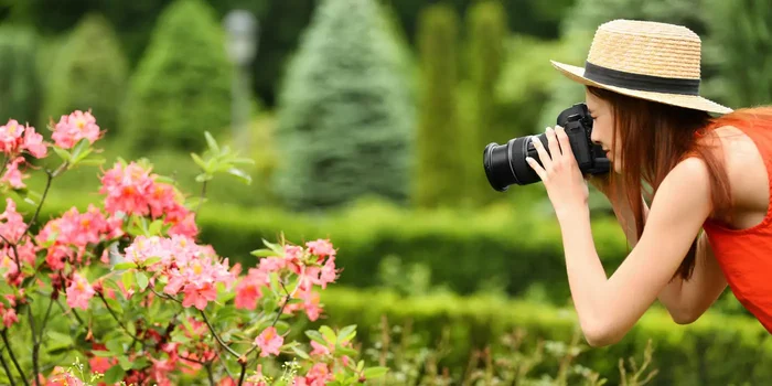 Eine Frau fotografiert Blumen mit einer Spiegelreflexkamera