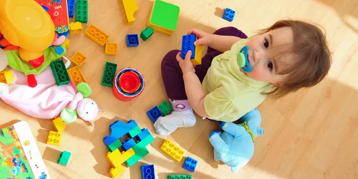 Ein Kind spielt auf dem Boden mit verschiedenem Spielzeug