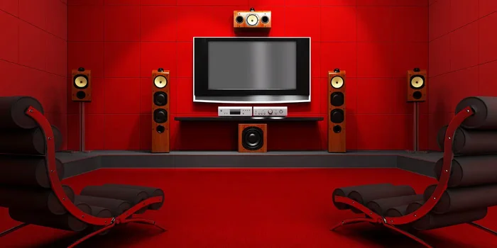 Ein 5.1 Surround-System mit TV und Receiver steht in einem Raum mit roten Wänden und zwei Liegen