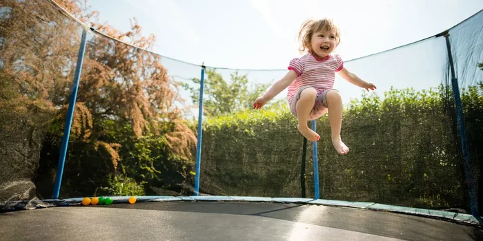 Ein Mädchen springt auf einem Gartentrampolin