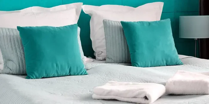 Stilvoll eingerichtetes Schlafzimmer mit farblich abgestimmten Kissen in türkis