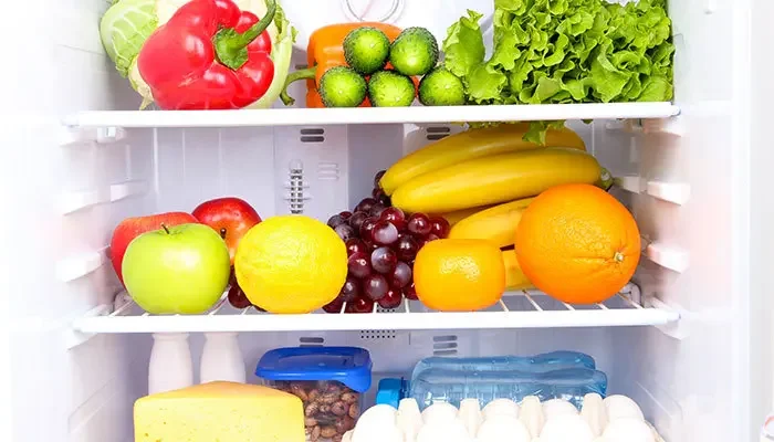 Aufnahme einen geöffneten Kühlschrankes, in dem sich viel Obst und Gemüse befindet.