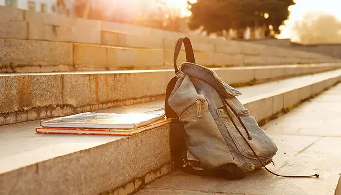 Aufnahme eines Rucksackes, welcher mit Büchern in der Sonne liegt.